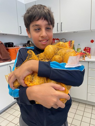 Ein Schüler trägt einen Sack Kartoffeln